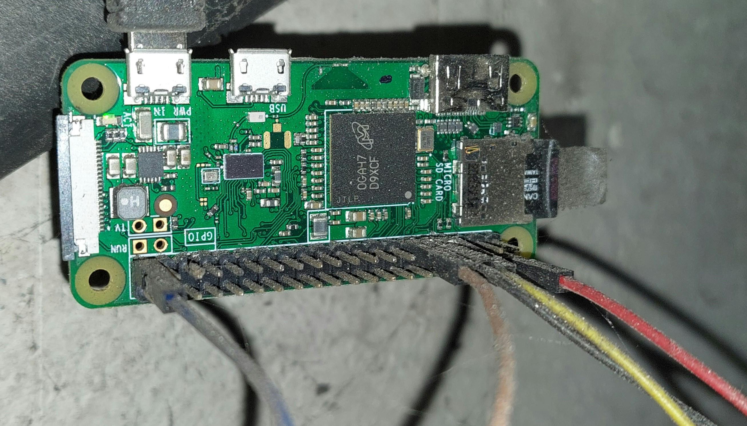 photo of a plugged in Raspberry Pi Zero W hanging on the wall with wires attached to the GPIO header
